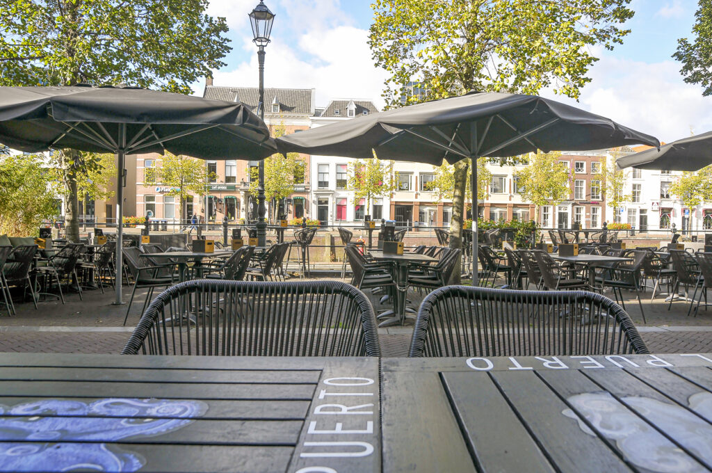 Het uitgebreide terras van El Puerto Breda met grote parasols aan de Haven